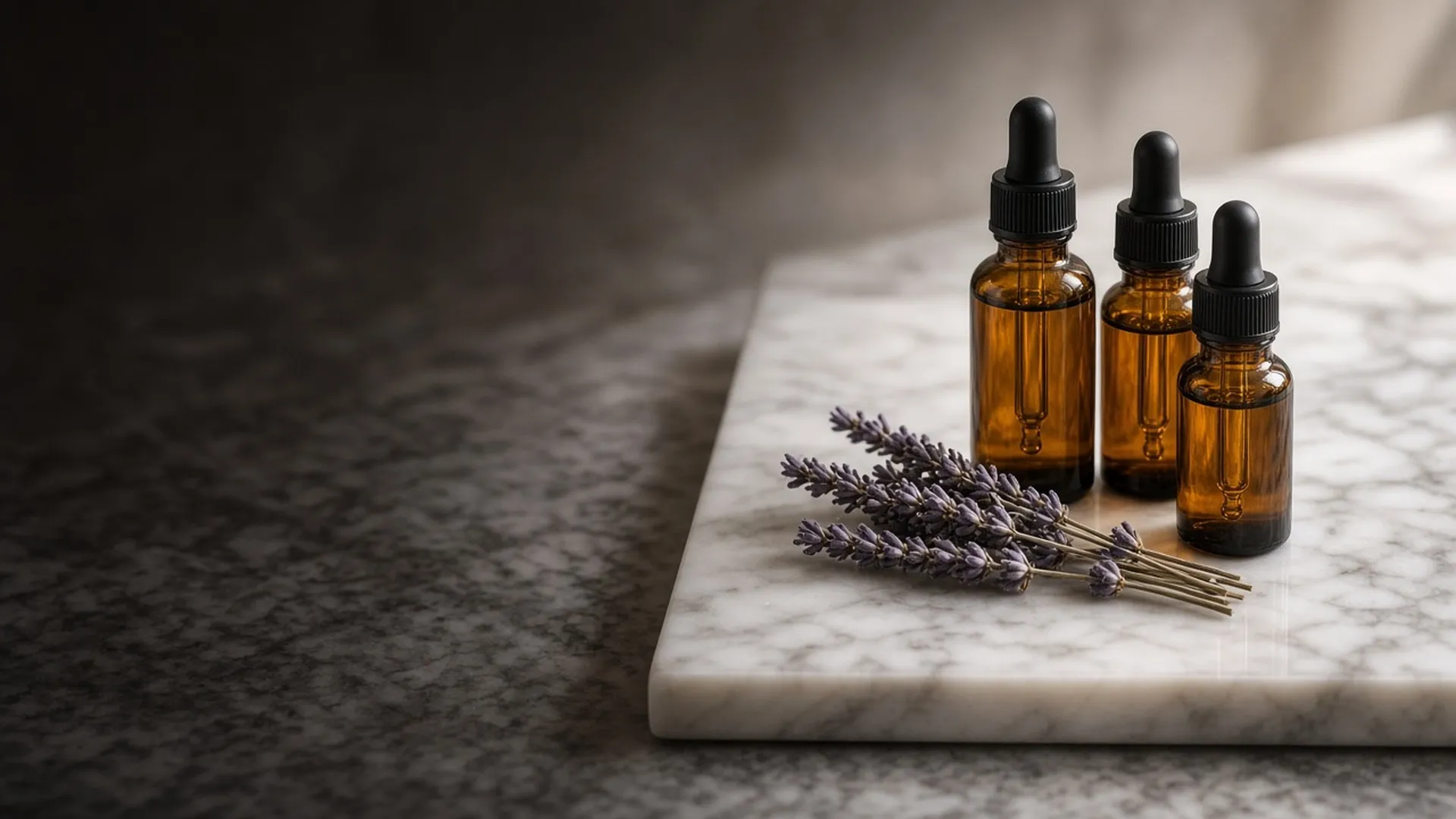 Unlabeled amber fragrance oil bottles with glass droppers on a marble tray